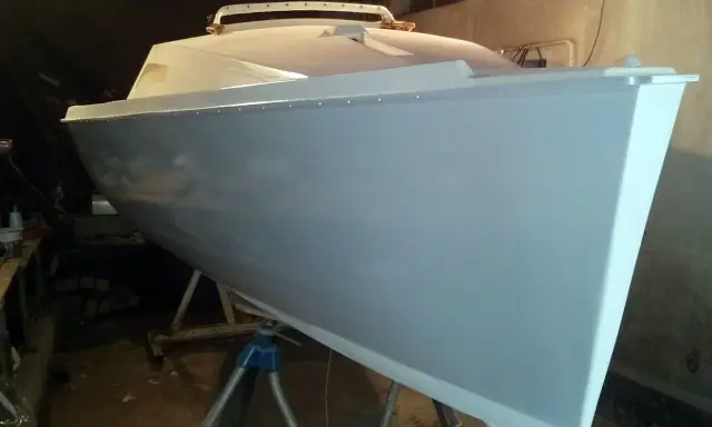 Le bateau Neptune 550, prêt pour sa nouvelle peinture, repose sur des supports dans un atelier.