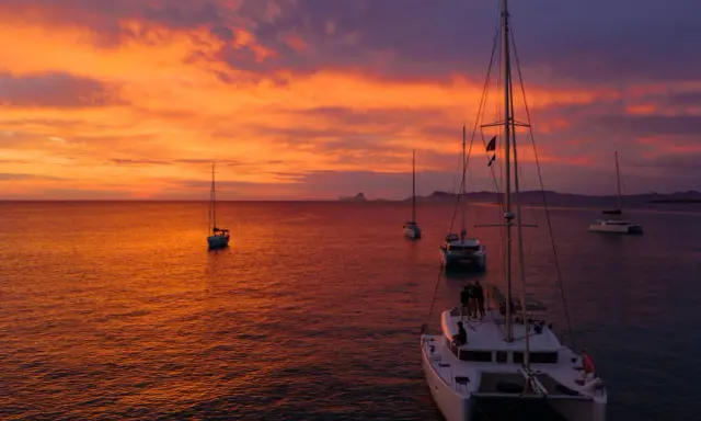 Coucher de soleil sur la mer avec des voiliers. Le tarif destruction bateau est une préoccupation pour certains, mais ici, la beauté règne.