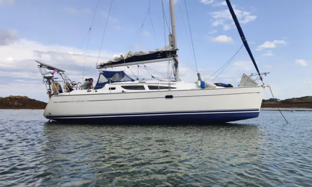 Un voilier Sun Odyssey 35, blanc avec une bande bleue, navigue paisiblement sur une mer calme. Les avis sur ce bateau sont positifs.