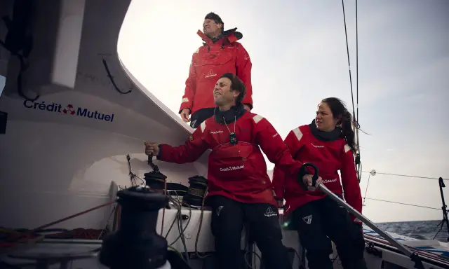 Amélie Grassi et son équipage en pleine action sur un voilier Crédit Mutuel. Le vent souffle, la mer est agitée.