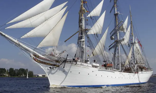 Le Statsraad Lehmkuhl, voilier blanc aux voiles gonflées, navigue fièrement, symbole du **general valor** des marins.