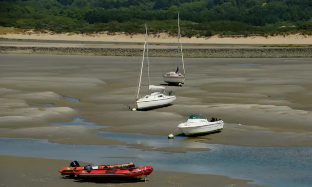 Trois voiliers et un bateau à moteur échoués sur la vase, avec un zodiac rouge au premier plan. Le **kelt 9** est l'un des voiliers.