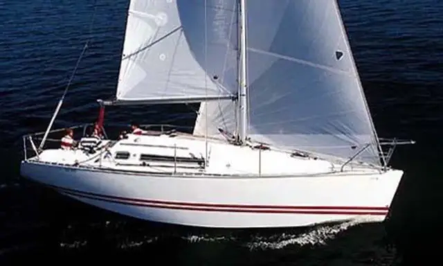 Voilier blanc à voiles gonflées, naviguant sur l'eau sombre. Les avis sur le Sun Fast 32 confirment sa rapidité.