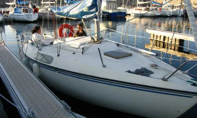 Deux personnes sur un voilier blanc, un Kelt 620, dans un port. Les avis sur ce bateau sont positifs.