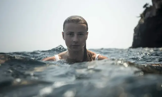 Marion Moriceau, le visage émergeant des vagues, le regard intense, baignée par la lumière du jour.
