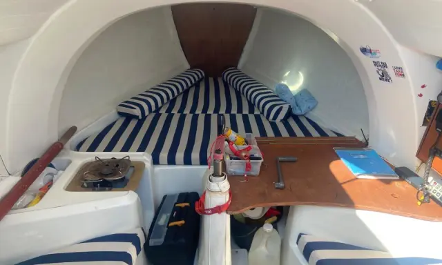 Intérieur du first 210, avec banquettes rayées bleu et blanc, réchaud, outils et bidon d'eau. Prêt pour l'aventure !