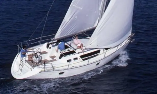 Trois personnes profitent d'une belle journée en mer à bord de voiliers occasion 9 10 mètres. Le bateau blanc navigue sur des eaux bleues.