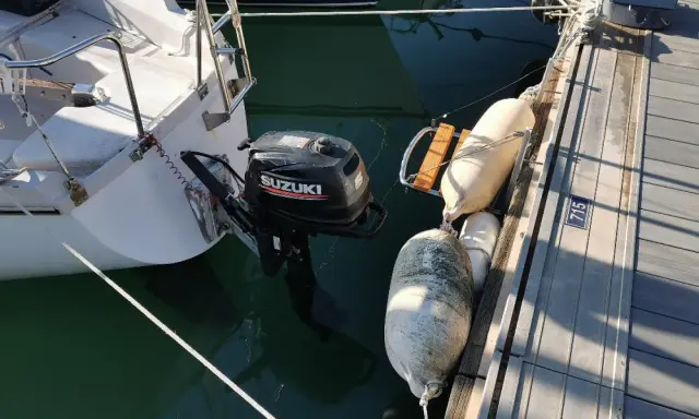 Un voilier "love love" amarré au ponton, avec un moteur Suzuki prêt à l'action. Des pare-battages protègent la coque.