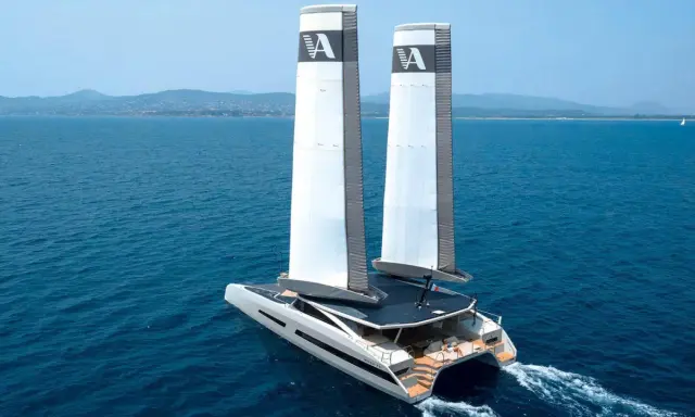 Le catamaran de luxe MODX 70 navigue sur une mer bleue, ses deux voiles imposantes portant le logo "A".