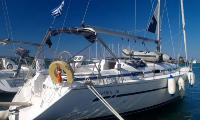 Voilier Bavaria 36 blanc amarré, pavillon grec, pare-battages bleus et blancs.