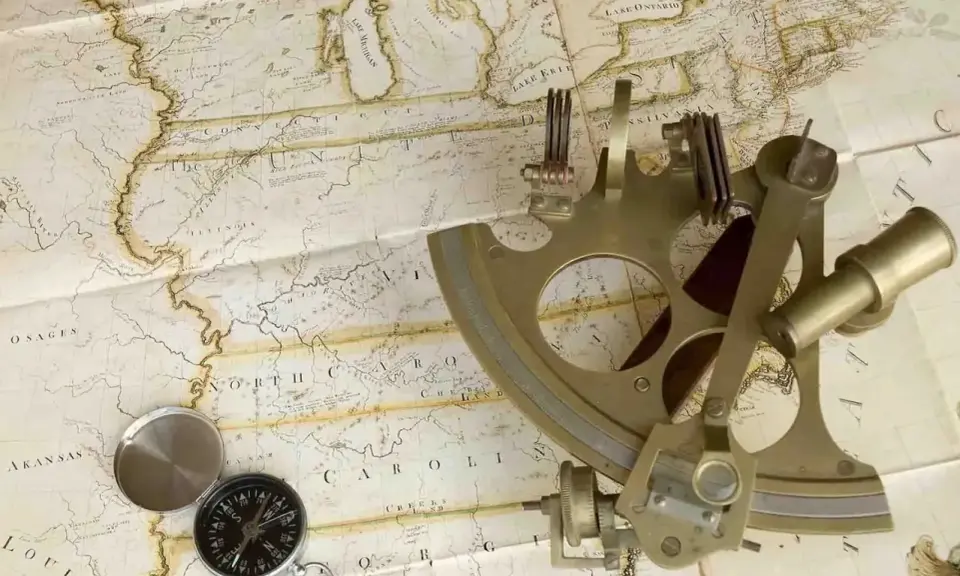 Un sextant et une boussole sur une carte ancienne, évoquant la navigation et l'exploration.