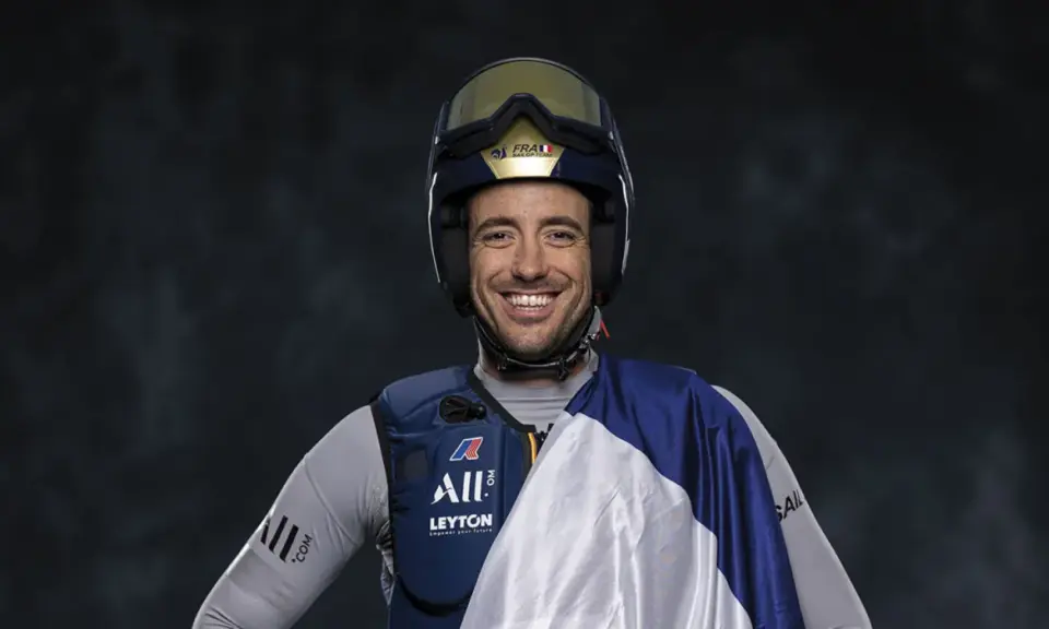 Quentin Delapierre, souriant, porte un casque de voile et une tenue de sport.