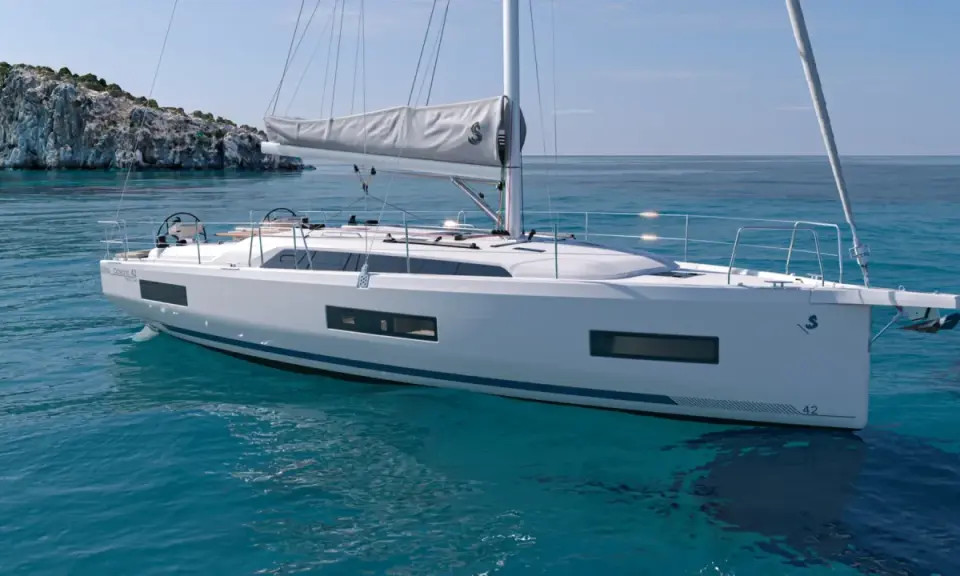 Un voilier blanc moderne navigue sur des eaux turquoise claires, près d'une île rocheuse. Ce modèle, le "Oceanis 42", pourrait bien être le meilleur voilier habitable pour vos aventures.