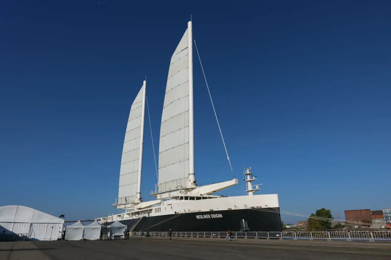 Le Neoliner Origin, un navire futuriste pour le transport &agrave; la voile, se dresse fi&egrave;rement sous un ciel bleu &eacute;clatant.