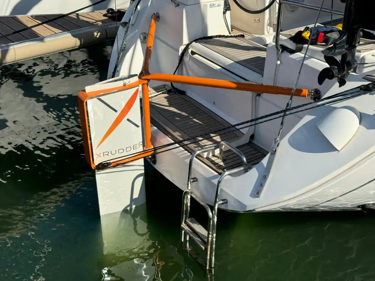 Le safran d'un catamaran est immergé dans l'eau verte, prêt pour une navigation.