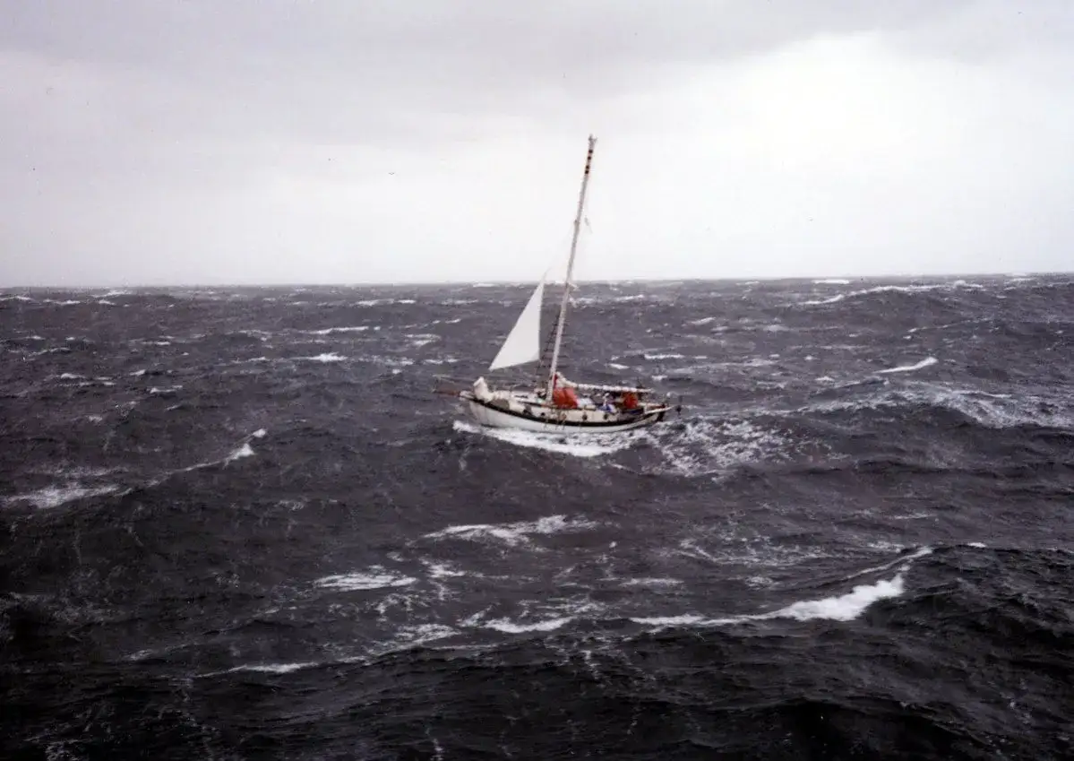 Un voilier affronte une mer agitée, sa voile blanche déployée. La mise à la cape est une manœuvre de survie face à la tempête.