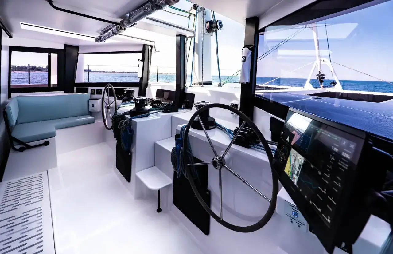 Cockpit moderne d'un voilier 902, avec un poste de pilotage, des écrans de navigation et une banquette bleue.