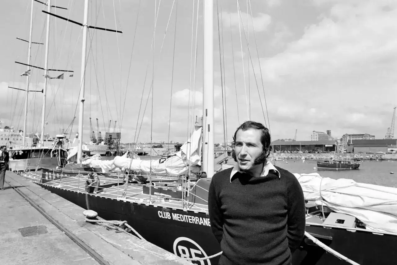 Un homme pose devant le voilier 