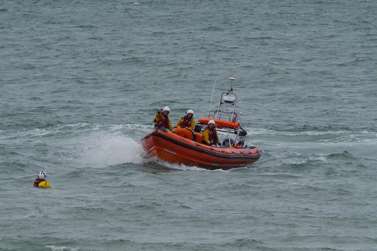 Bateau de sauvetage orange avec équipage en action. Une personne dans l'eau, une fusée de détresse bateau obligatoire est essentielle pour la sécurité.