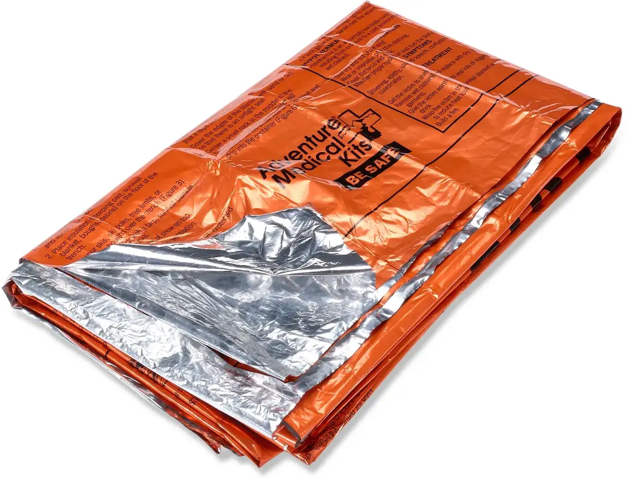 Couverture de survie orange et argentée, pliée, avec des instructions imprimées. Essentielle pour la sécurité en cas d'urgence.
