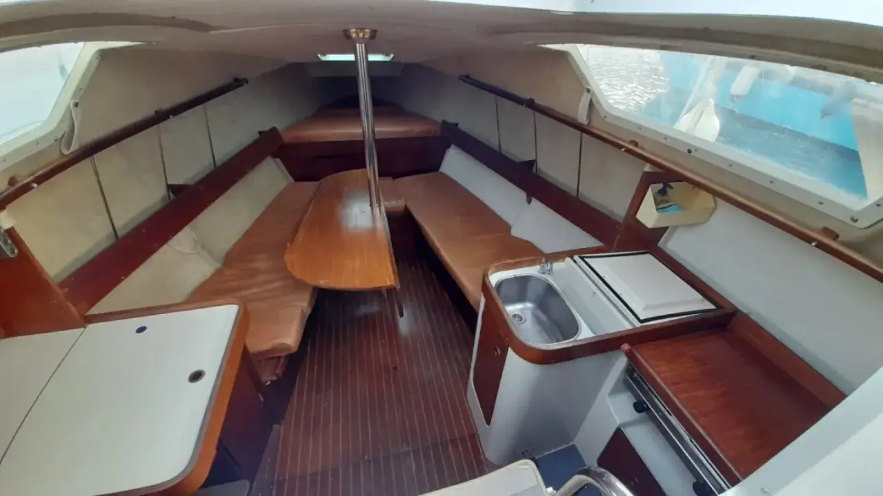 Intérieur d'un voilier avec banquettes en cuir, table en bois et évier. Le gib sea 76 avis est prêt pour l'aventure.