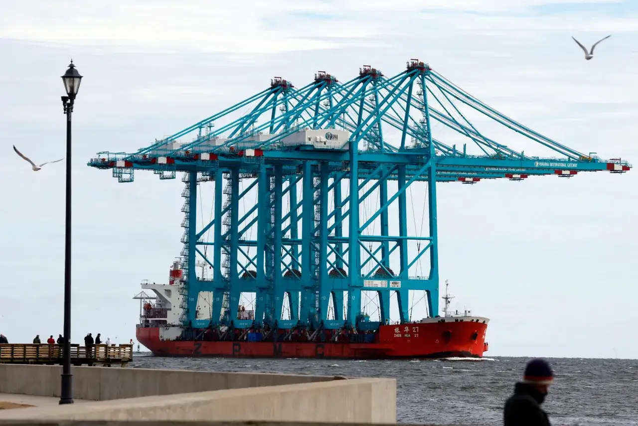 Un navire transporte plusieurs grues bleues géantes, démontrant une impressionnante capacité porte conteneur.