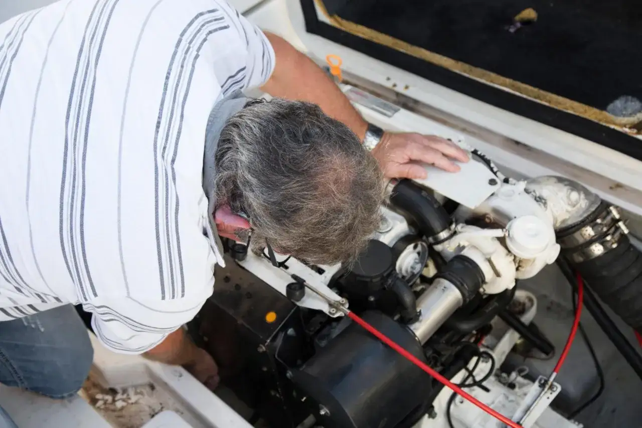 Un mécanicien vérifie le moteur inboard d'un bateau, s'assurant de sa bonne maintenance pour optimiser la durée de vie du moteur.