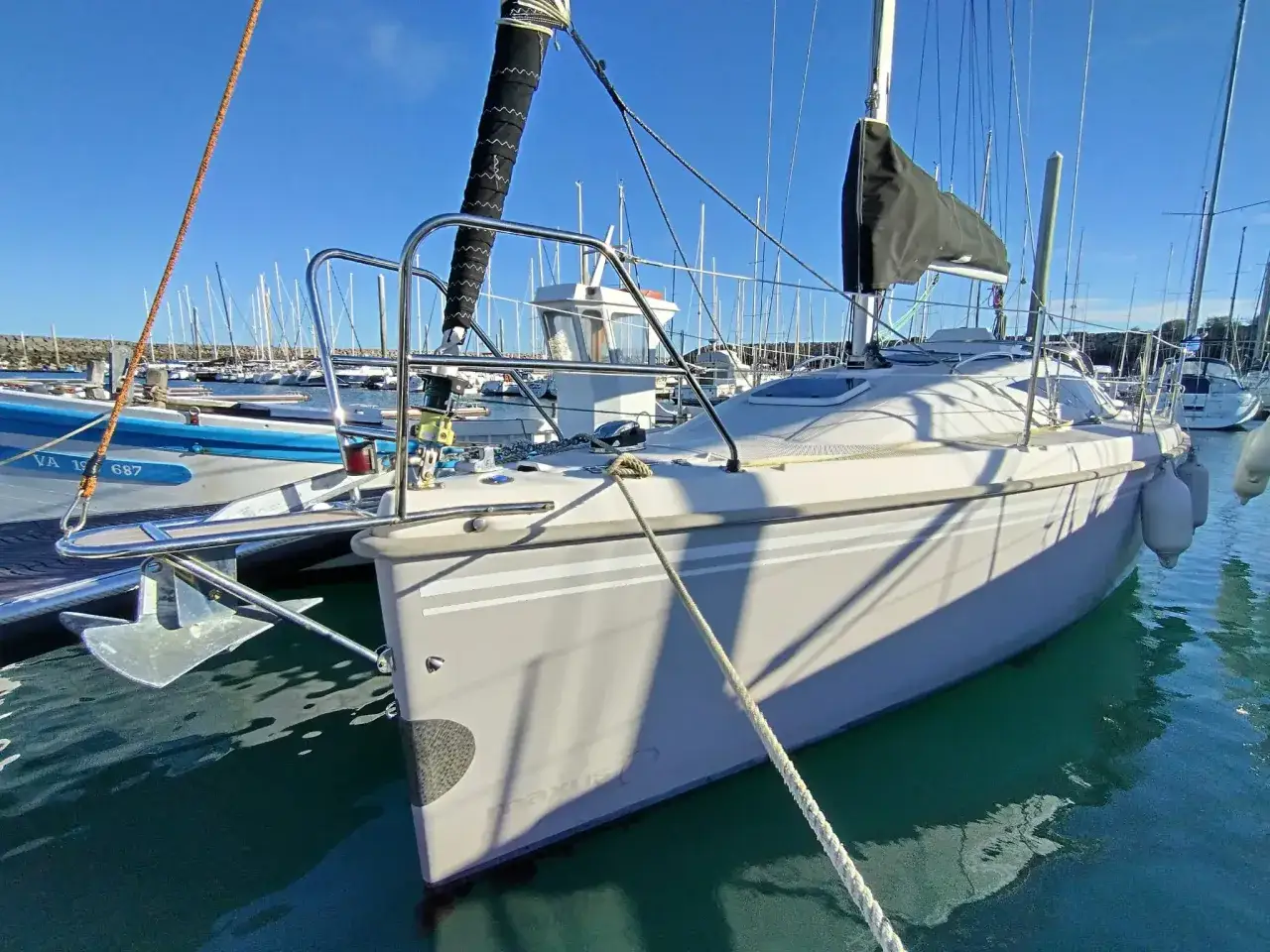 Un voilier Maxus 6.1, prêt pour l'aventure, est amarré dans un port sous un ciel bleu éclatant.