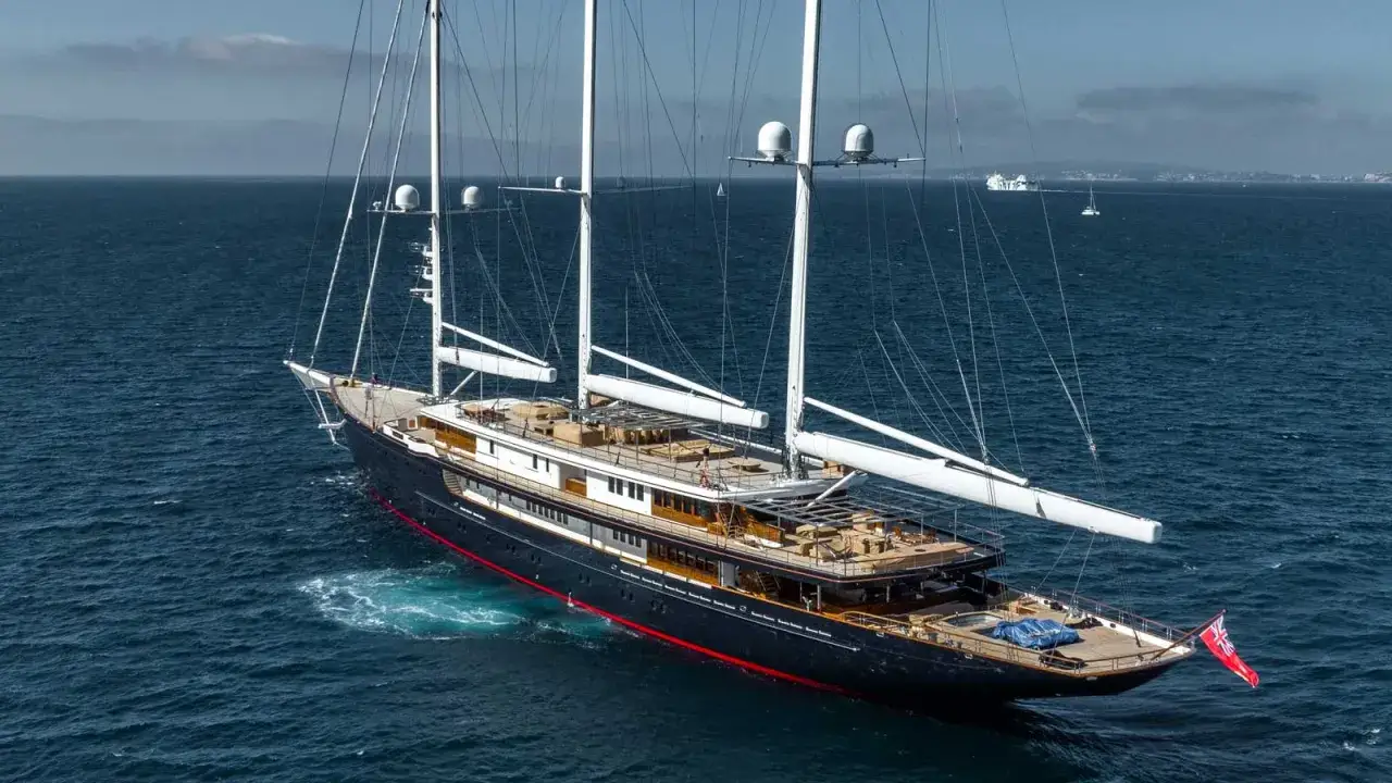 Le yacht Koru, le yacht de Jeff Bezos, navigue sur une mer bleue. Ce voilier imposant est doté de trois mâts et de plusieurs ponts.