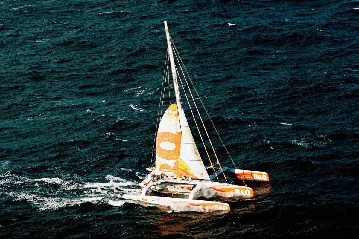 Trimaran B&Q, le compagnon d'Ellen MacArthur, fend les vagues sombres.