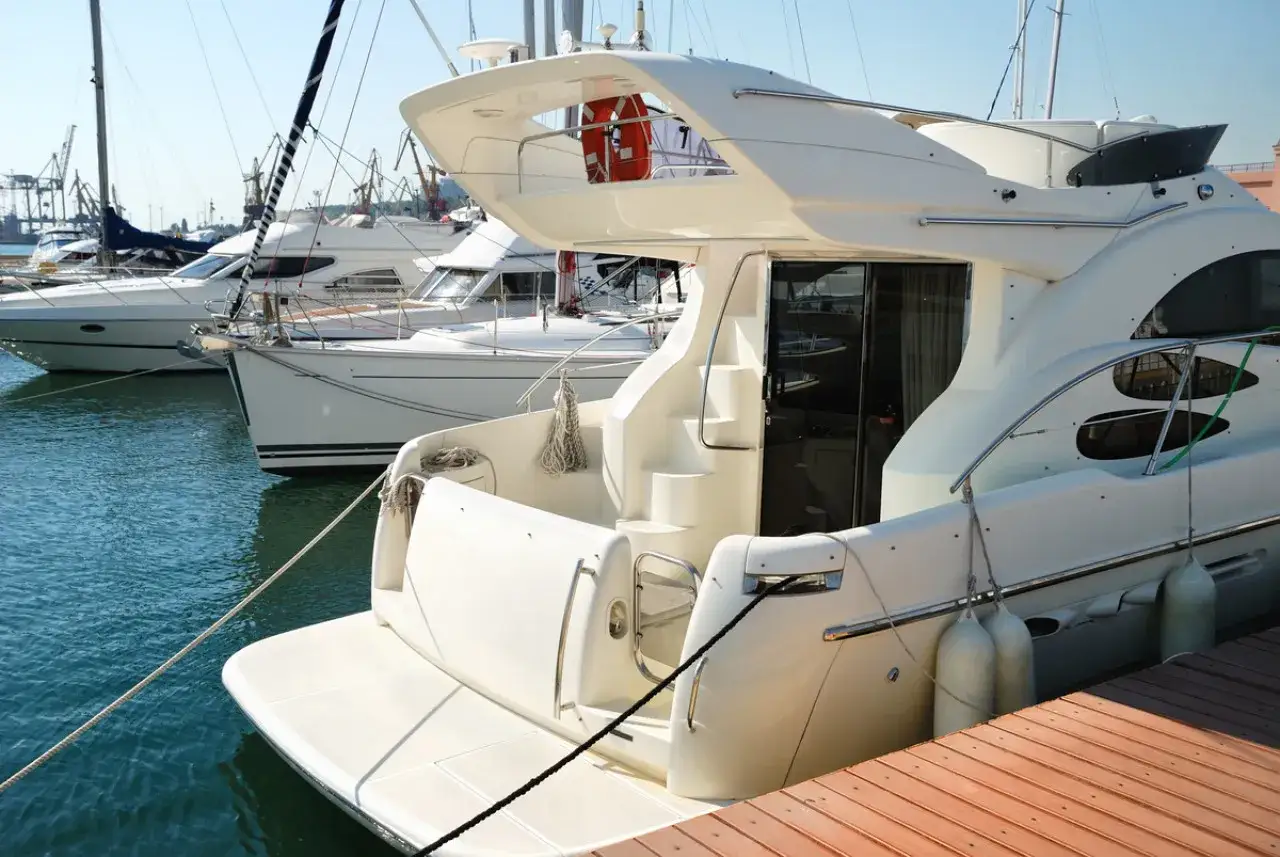 Yacht blanc amarré, prêt pour un compromis vente bateau. D'autres voiliers et grues en arrière-plan.