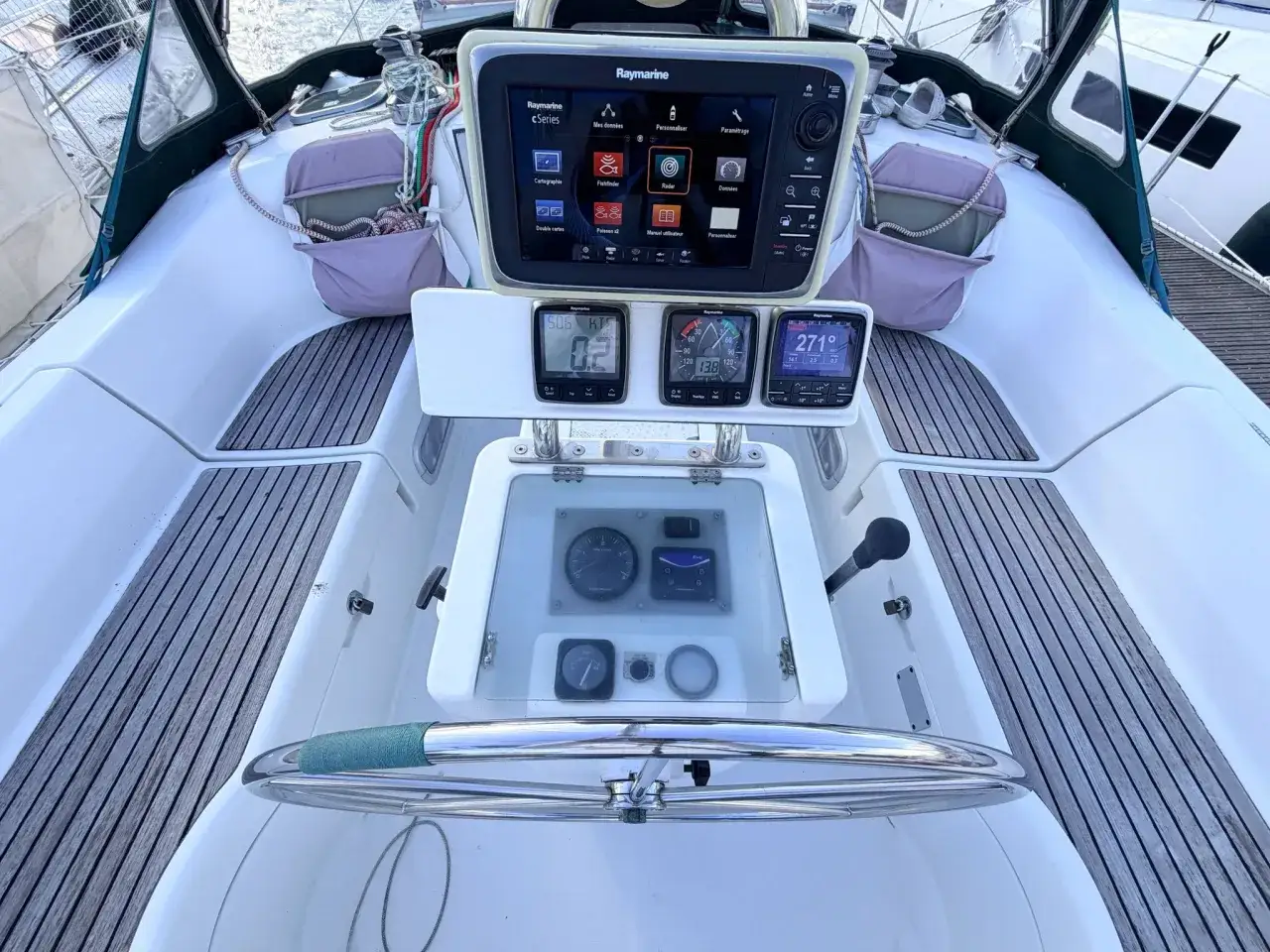 Cockpit d'un voilier, avec écran Raymarine C Series affichant le radar. Instruments de navigation et barre à roue. Fiche technique Oceanis 351.
