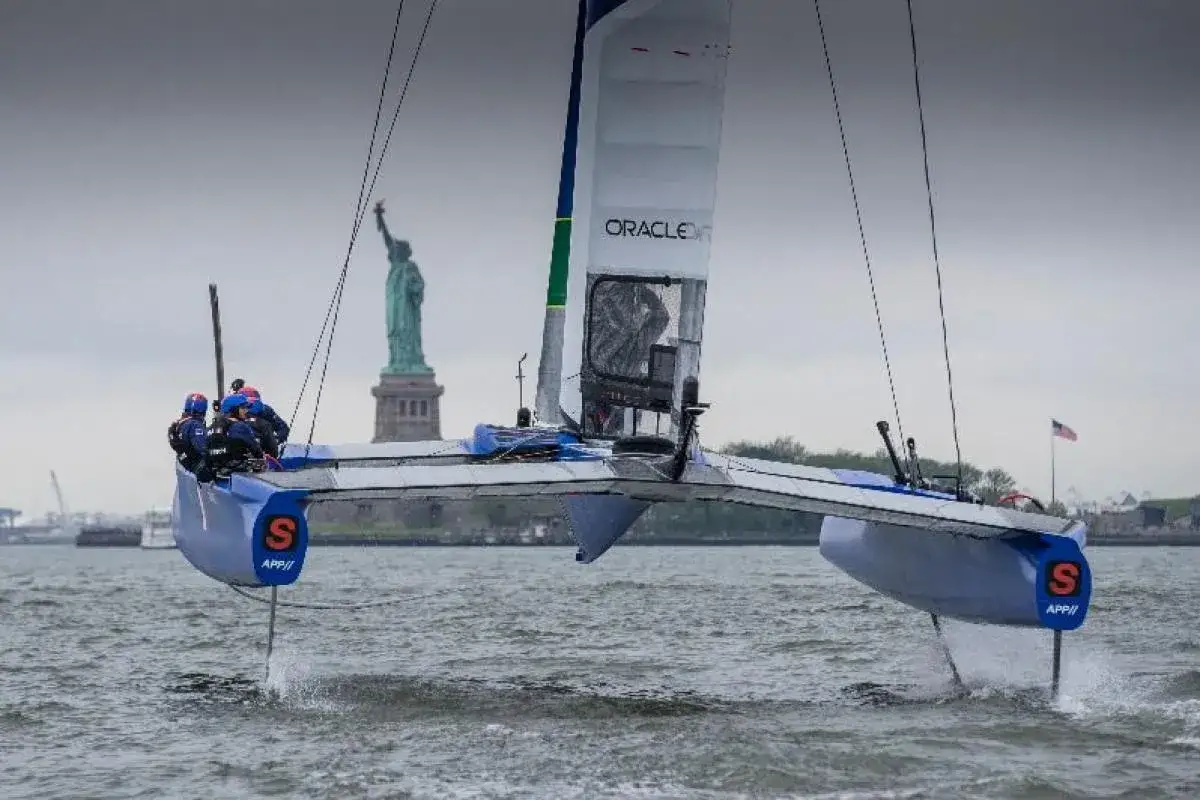 Un catamaran de course Oracle, avec l'&eacute;quipage de Billy Besson, fend les vagues pr&egrave;s de la Statue de la Libert&eacute;.