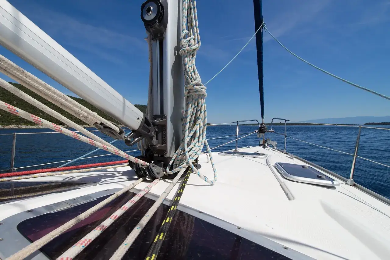 Vue de l'avant d'un voilier naviguant sur une mer bleue. Les cordages sont bien rang&eacute;s, pr&ecirc;ts pour le prochain hale bas.