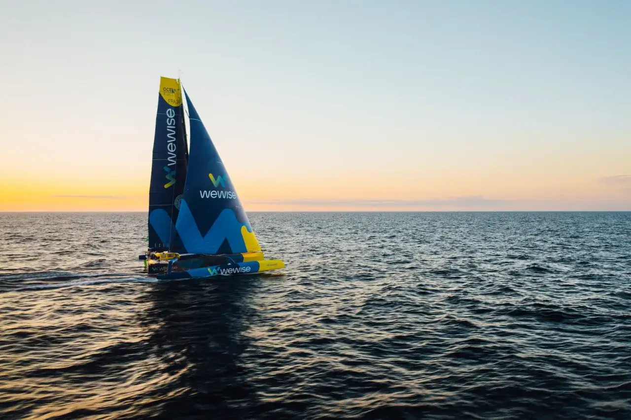 Un catamaran de course aux voiles bleues et jaunes, marqué