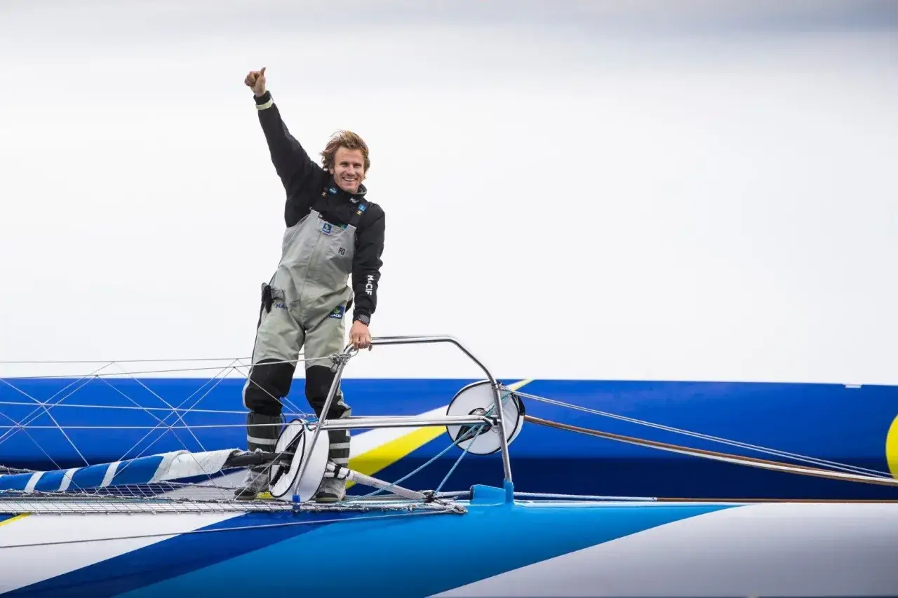 Victoire pour Gabart ! Le skipper célèbre sa réussite sur son voile lors d'une transat.