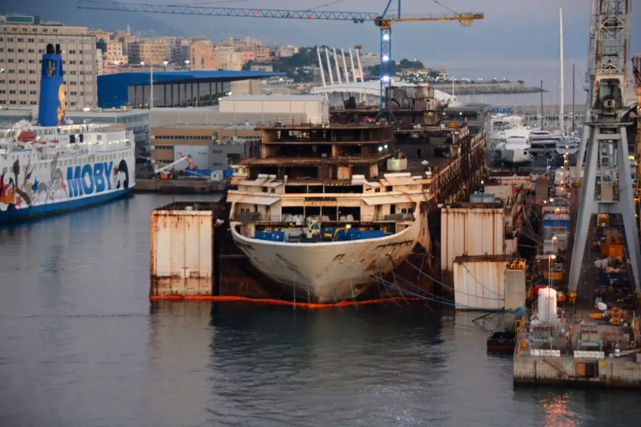 Le Costa Concordia, en démolition, est amarré dans une cale sèche, entouré d'autres navires et de grues.