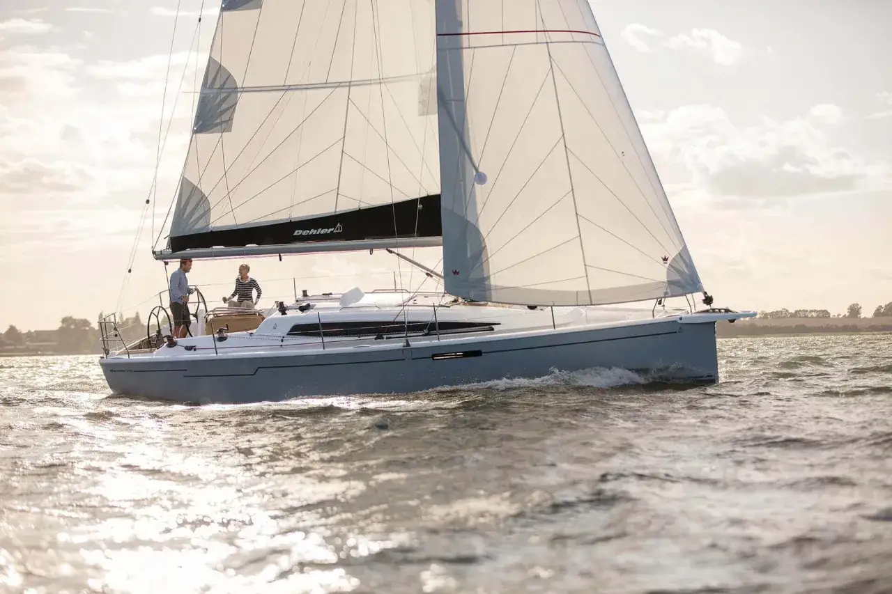 Un voilier Dehler 34 navigue par beau temps. Les voiles sont hissées, deux personnes sont à bord.