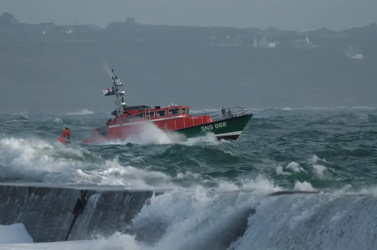 Un bateau de sauvetage rouge et vert, SNS 068, affronte des vagues déchaînées. Ce bateau dans la tempête navigue courageusement en mer.