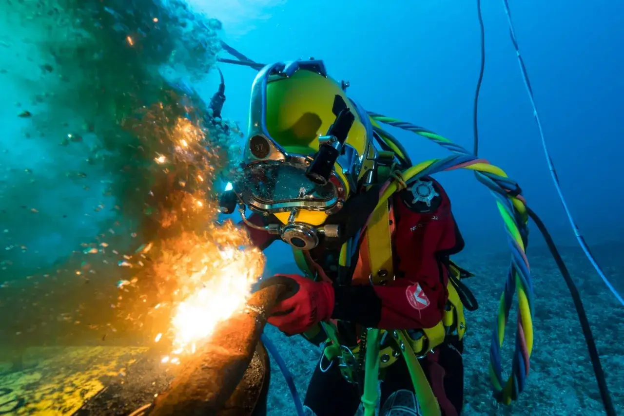 Plongée sous-marine : Marion Moriceau, scaphandrier, réalise une soudure sous-marine, créant un spectacle de lumière et d'étincelles dans les profondeurs bleues.