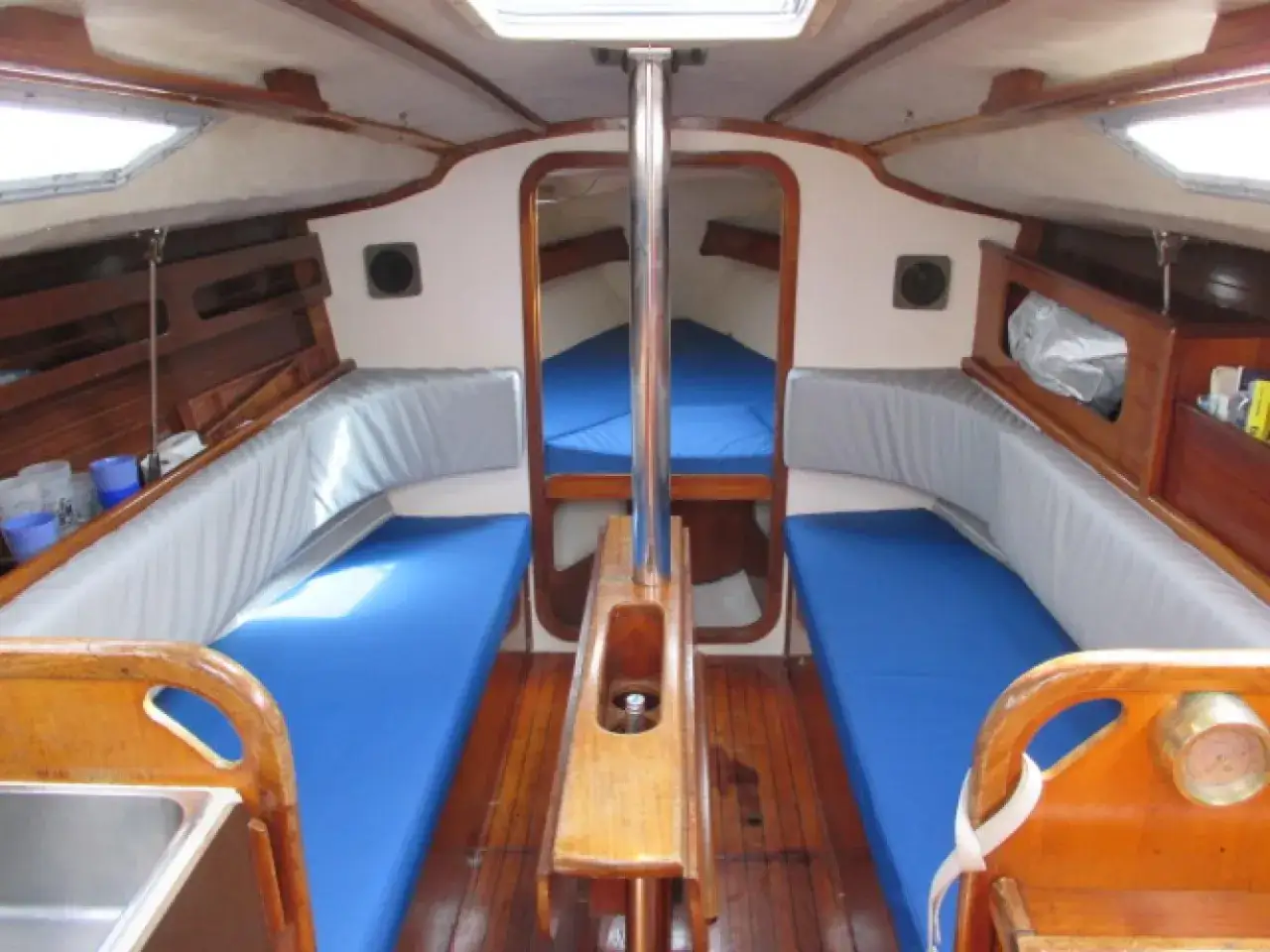 Intérieur d'un voilier Kelt 9, avec banquettes bleues et coussins gris, prêt pour une nouvelle aventure en mer.