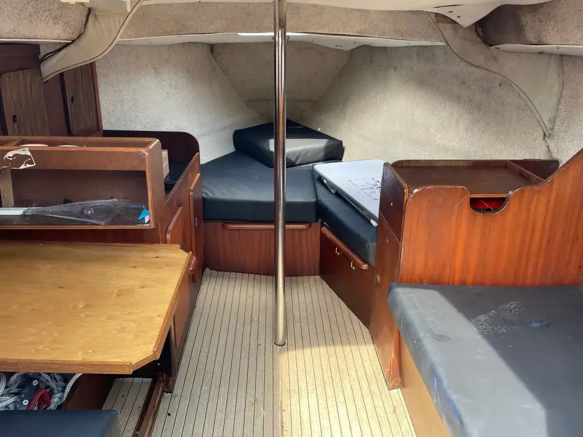 L'intérieur du Jeanneau Brio offre des banquettes confortables, une table en bois et des rangements pratiques, prêt pour de nouvelles aventures nautiques.