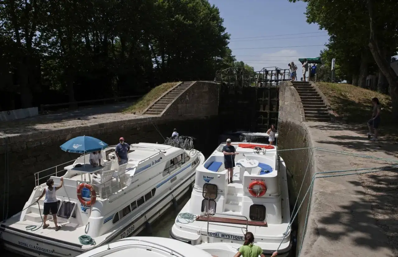 Deux bateaux de plaisance se préparent à remonter la vilaine en bateau, passant une écluse sous un ciel bleu.