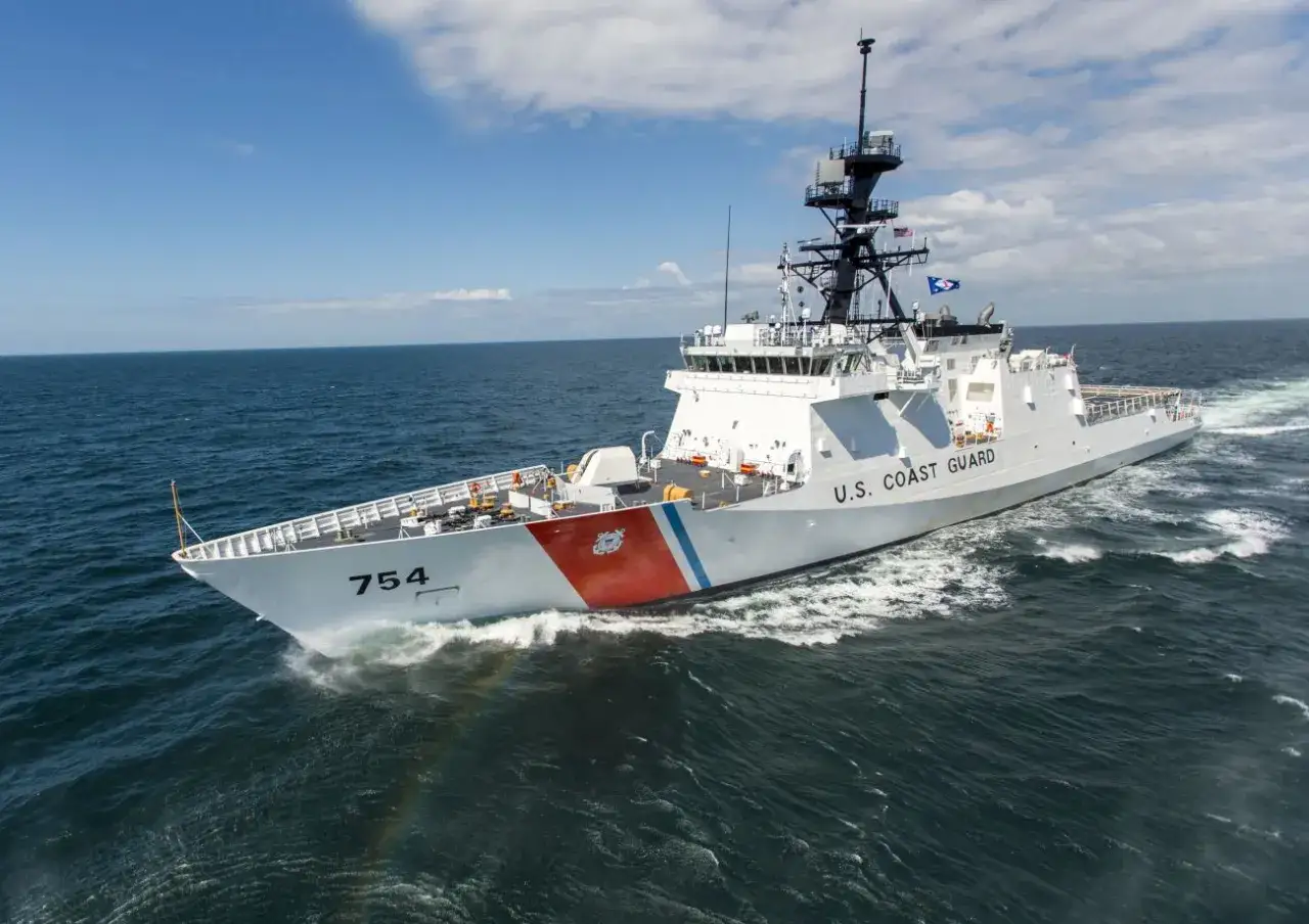 Un navire blanc du garde c&ocirc;te am&eacute;ricain, le num&eacute;ro 754, fend les vagues bleues sous un ciel nuageux.