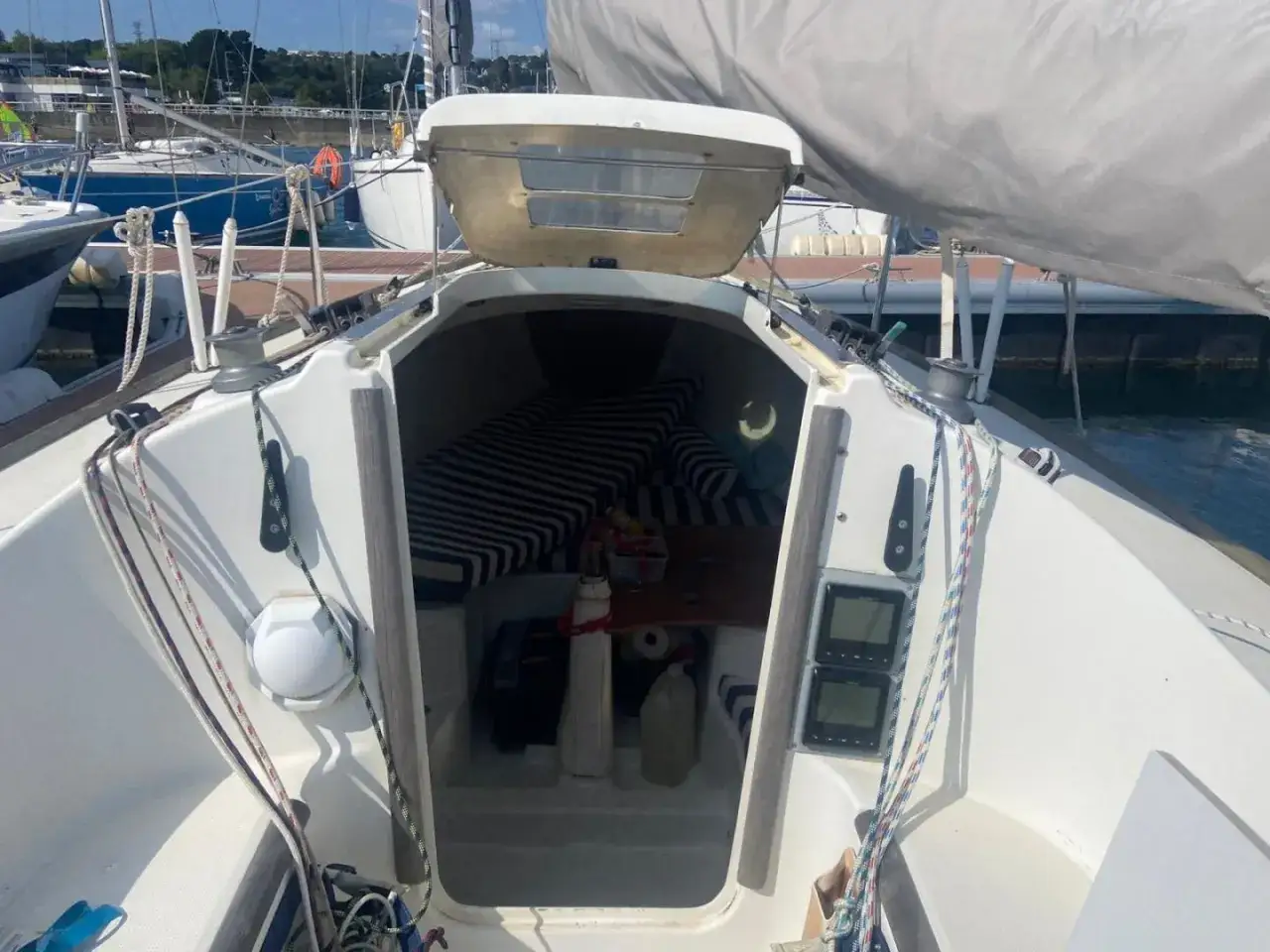 Vue de l'intérieur d'un voilier, cabine avec banquettes rayées. Le premier 210 fiche technique est prêt pour l'aventure.