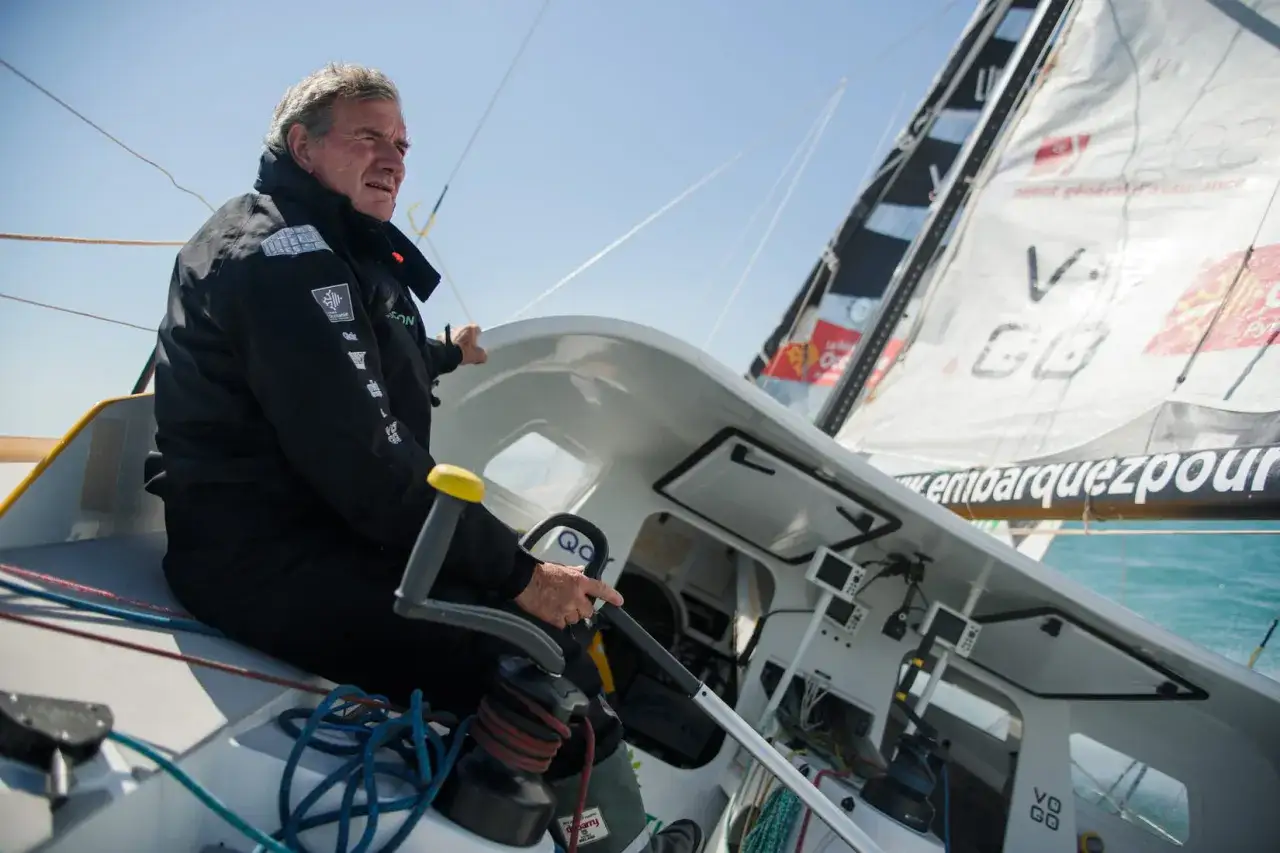 Un skipper expérimenté, kito de pavant, tient la barre d'un voilier, concentré sur la course.
