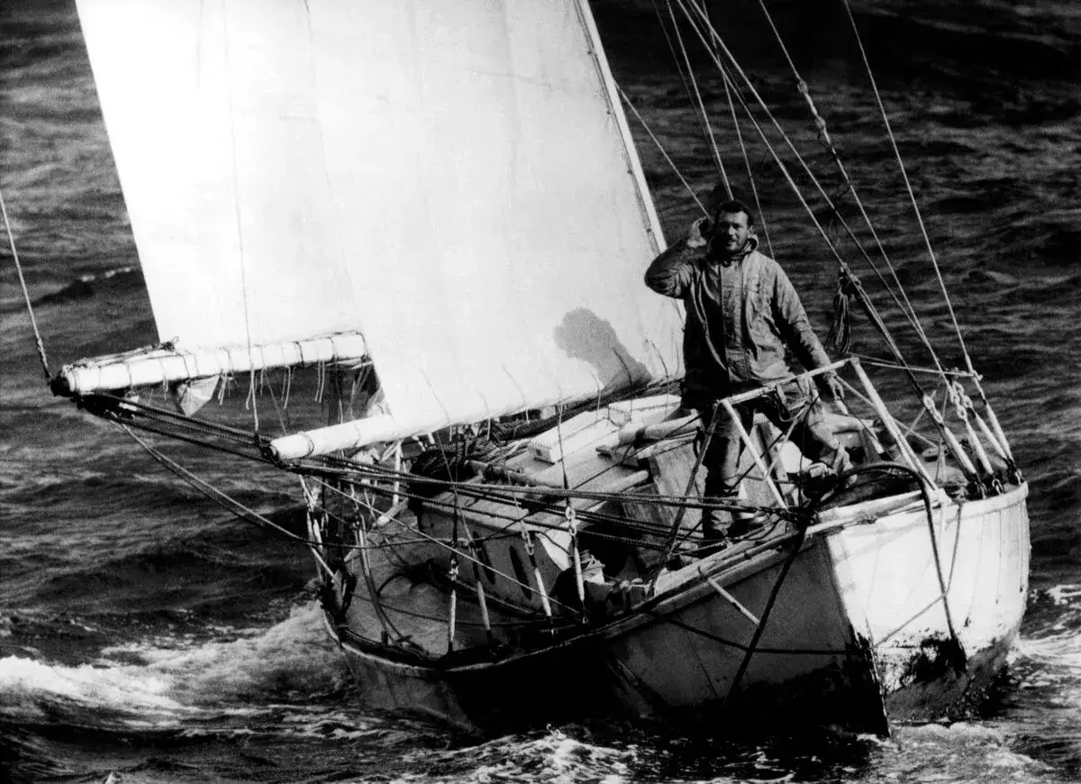 Robin Knox-Johnston, seul à bord de son voilier, salue au milieu des vagues.