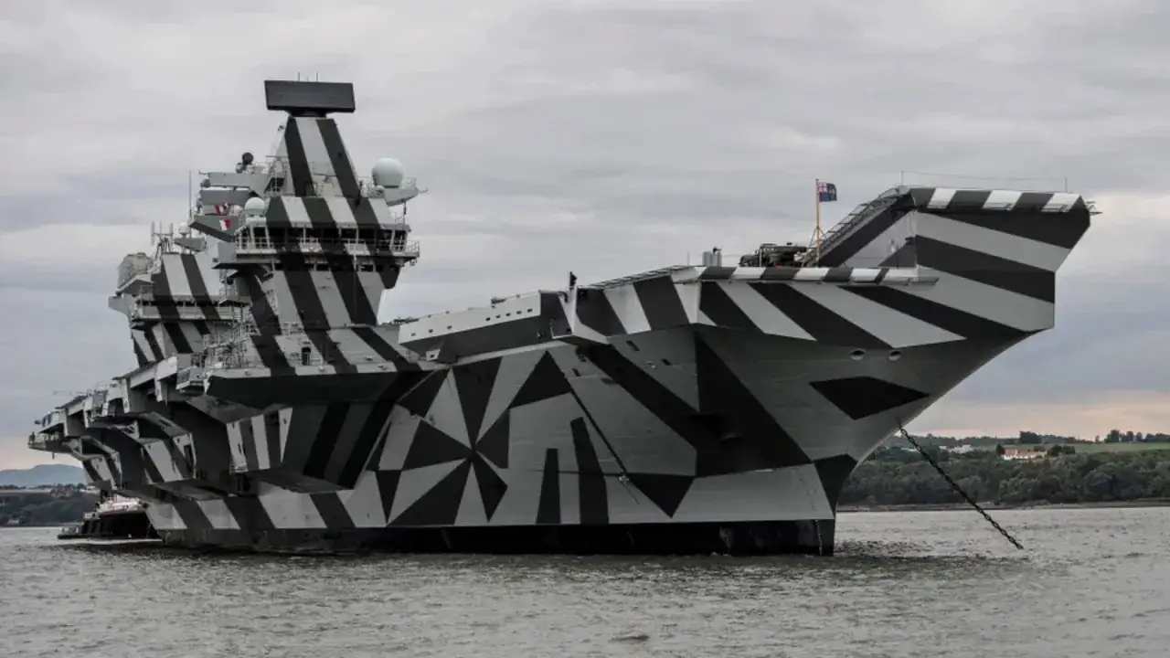 Porte-avions militaire au camouflage audacieux, ses formes géométriques noires et grises le rendent unique.