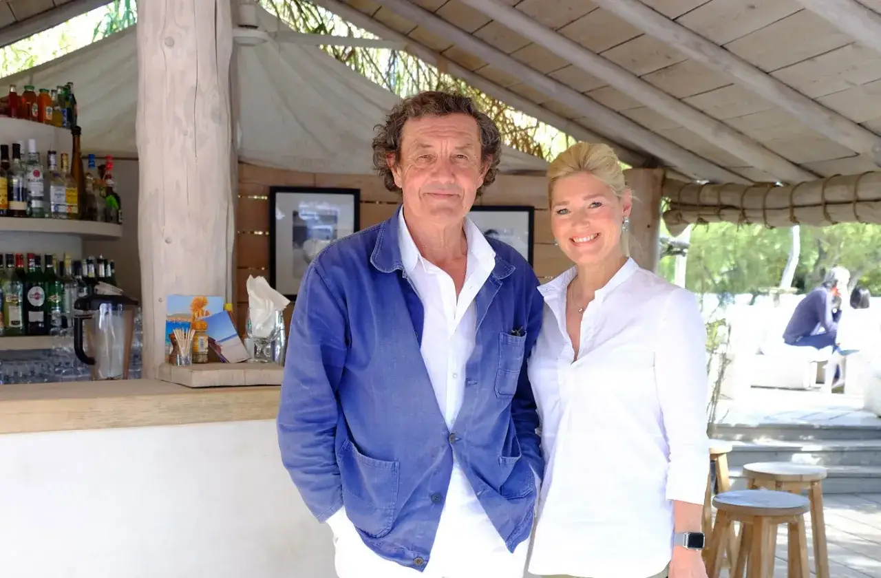 Patrice de Colmont et une femme souriante posent devant un bar.