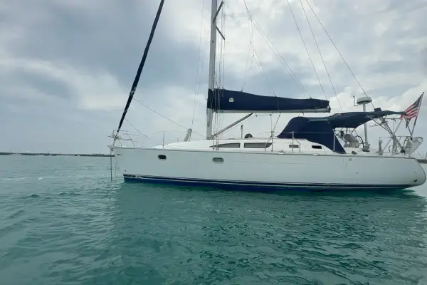 Voilier blanc à l'ancre, voiles bleues repliées. Un avis sur le Sun Odyssey 37, prêt pour l'aventure.